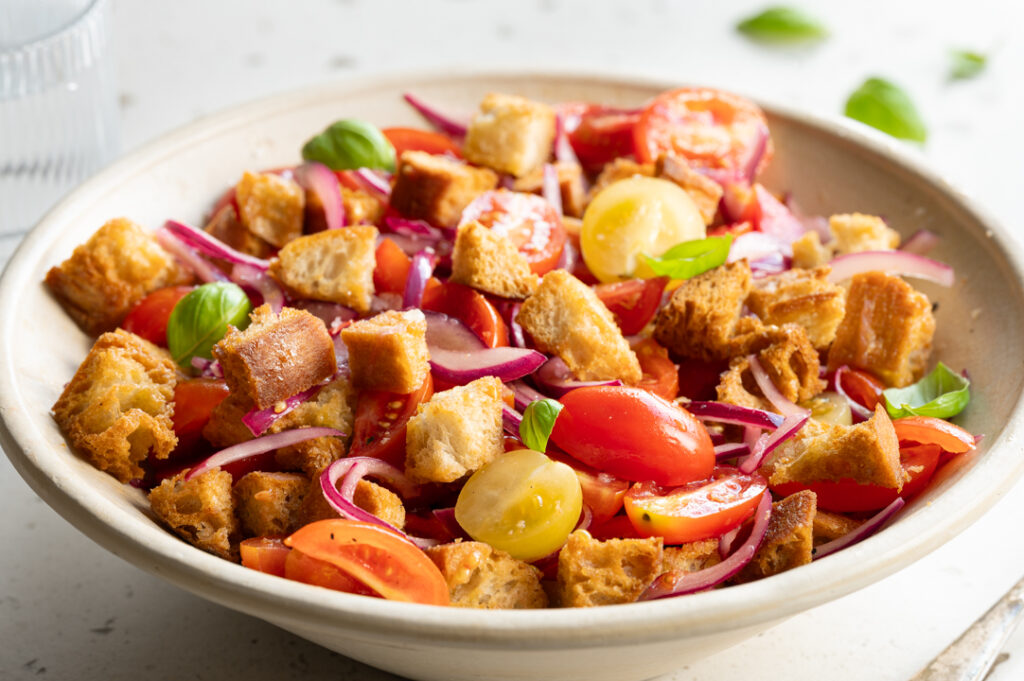 Ein Teller mit italienischem Brotsalat mit Tomaten steht auf einem Tisch.