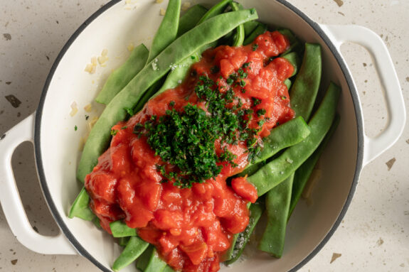 Die grünen Bohnen und die Tomaten sind in der Pfanne.