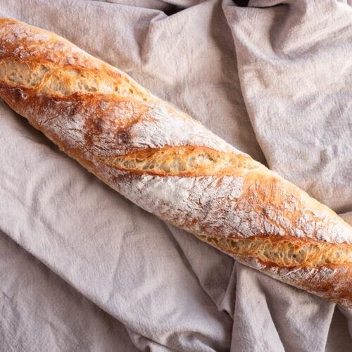 Ein französisches Baguette liegt auf einem Tuch.