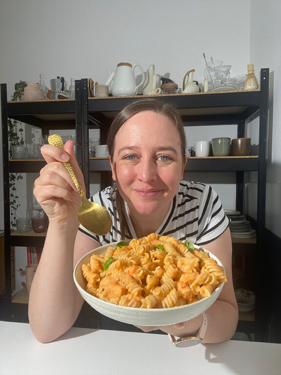 Eine Frau isst eine große Portion der Pasta mit Paprikasauce.