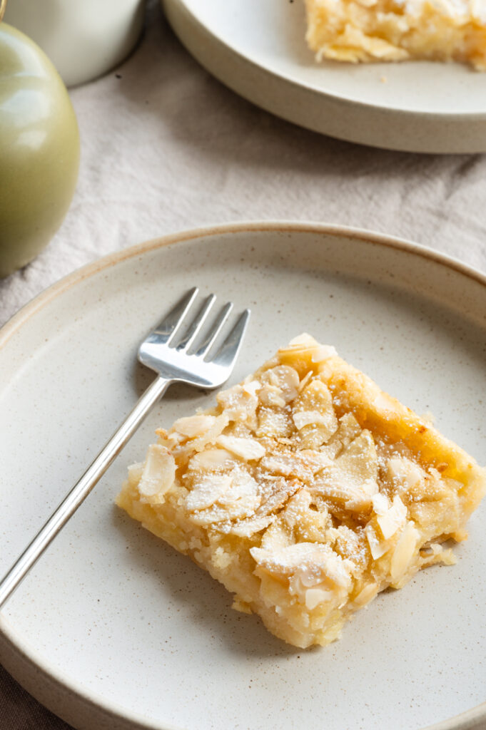 Ein gedeckter Tisch mit zwei Tellern, auf dem je ein Stück Apfelkuchen liegt.