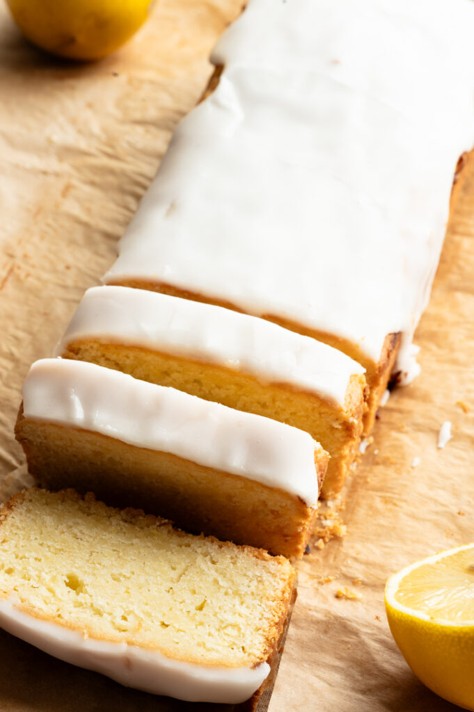 Der angeschnittene Zitronenkuchen liegt auf einem Backpapier.