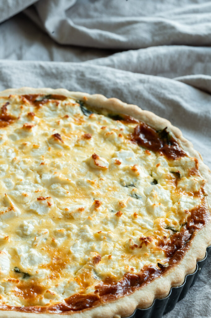 Eine Quiche mit Spinat und Feta steht auf dem Tisch.