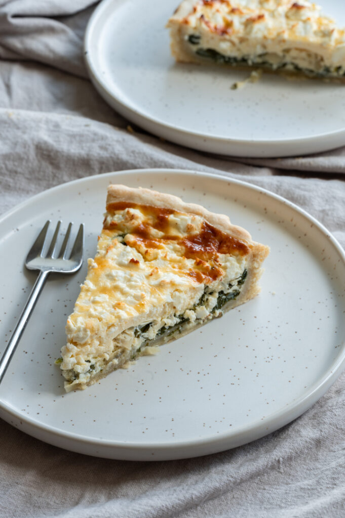 Zwei Teller mit je einem Stück Spinatquiche stehen auf dem Tisch.