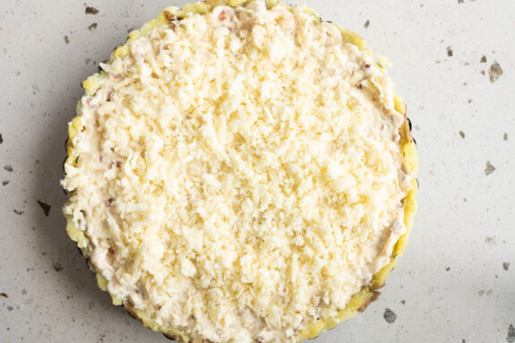 Der fertig belegte Zwiebelkuchen ist in einer Tarteform.